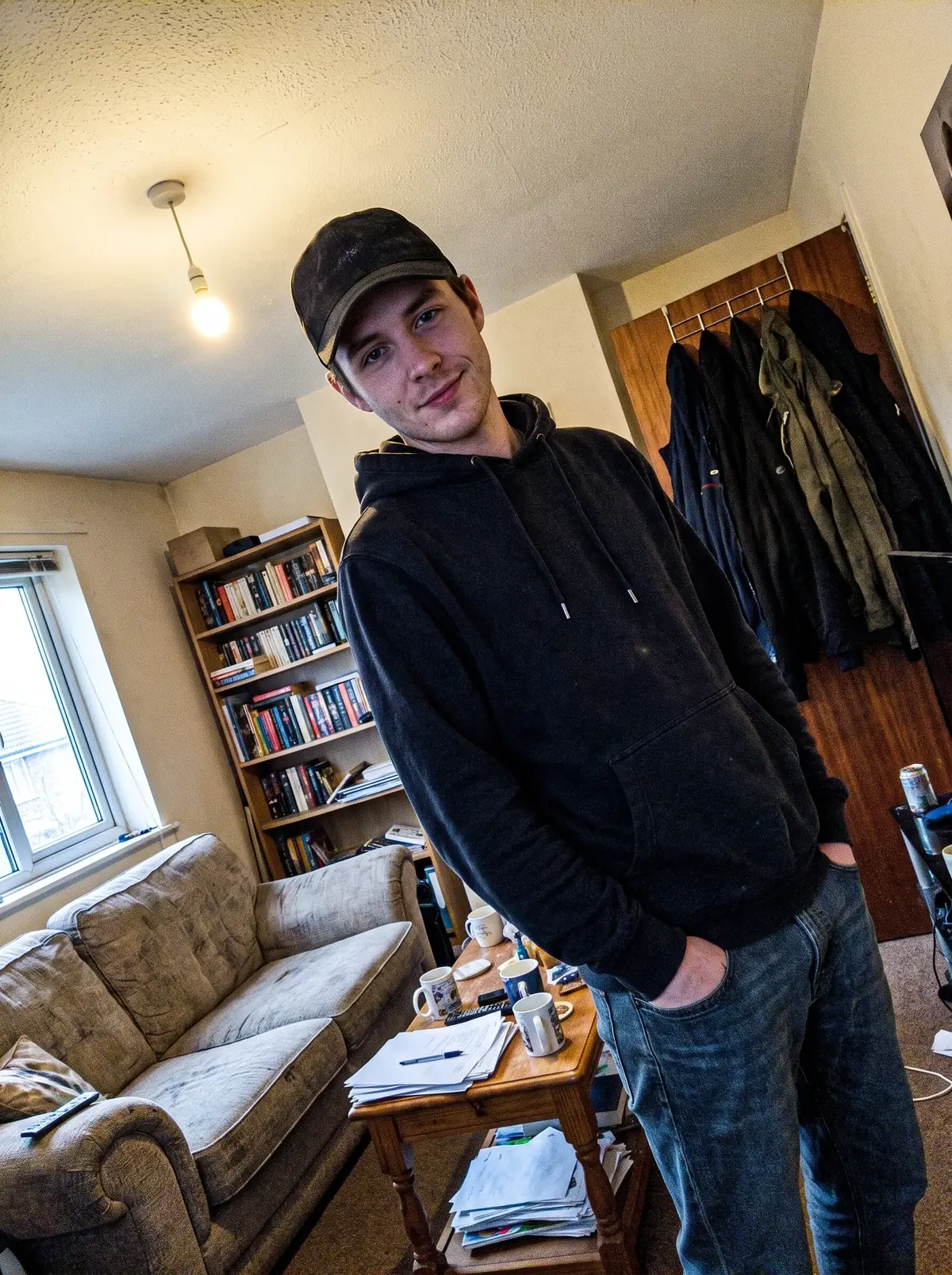 The photo we worked from: in the living room, cap and black hoodie.